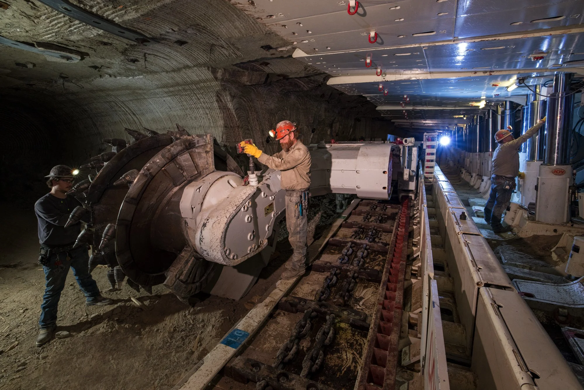 Workers installing tunnel boring machine inside an underground tunnel.