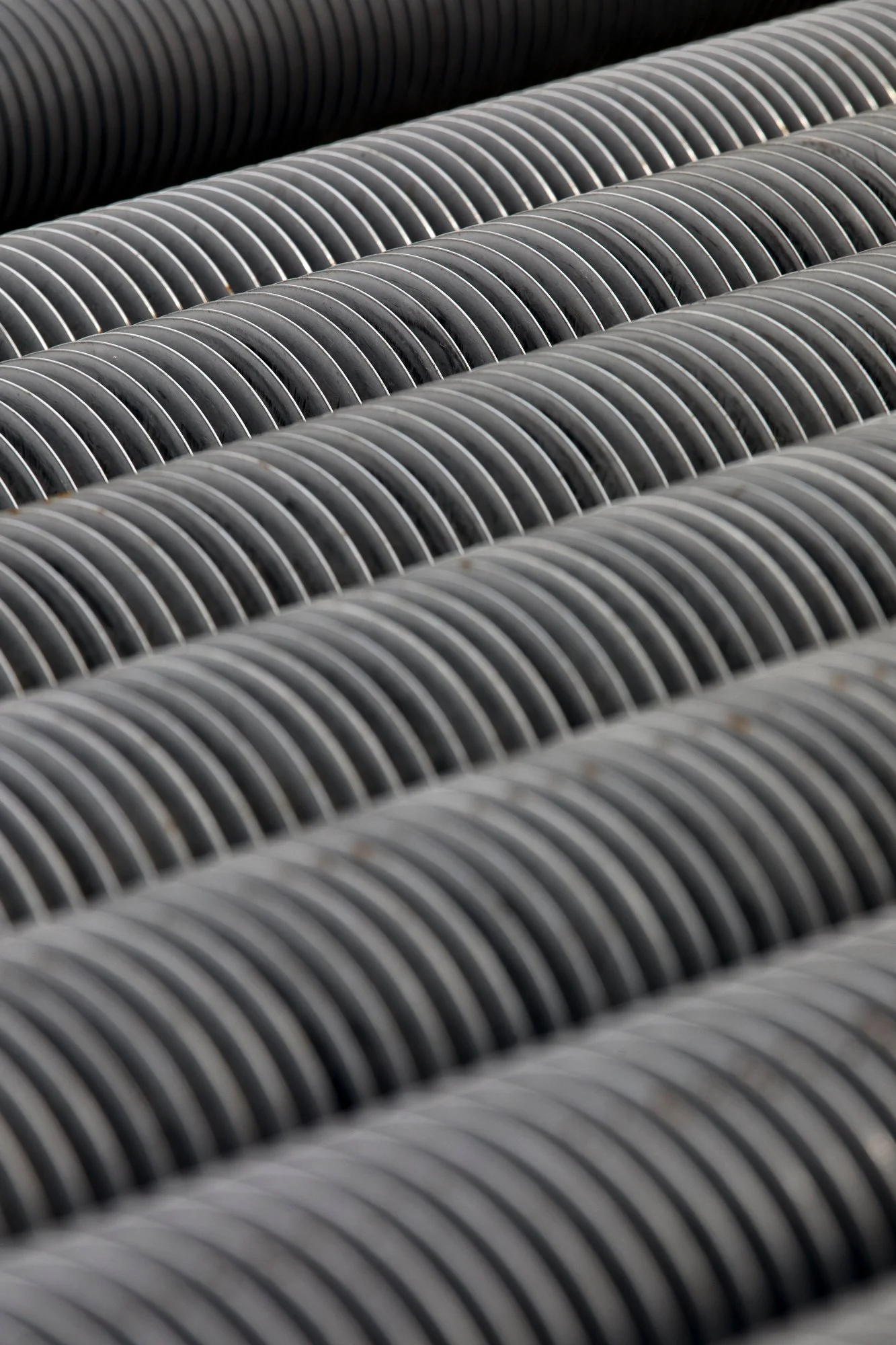 Multiple black and gray corrugated pipes arranged parallel to each other.