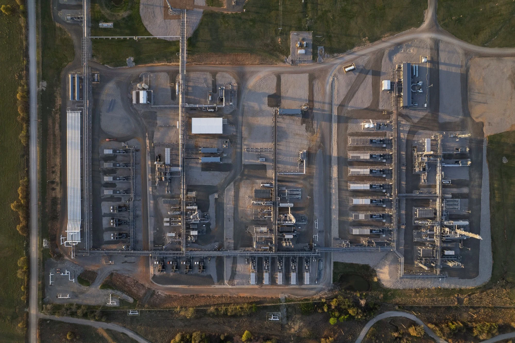 Aerial view of an electrical substation with transformers, circuit breakers, and power lines.