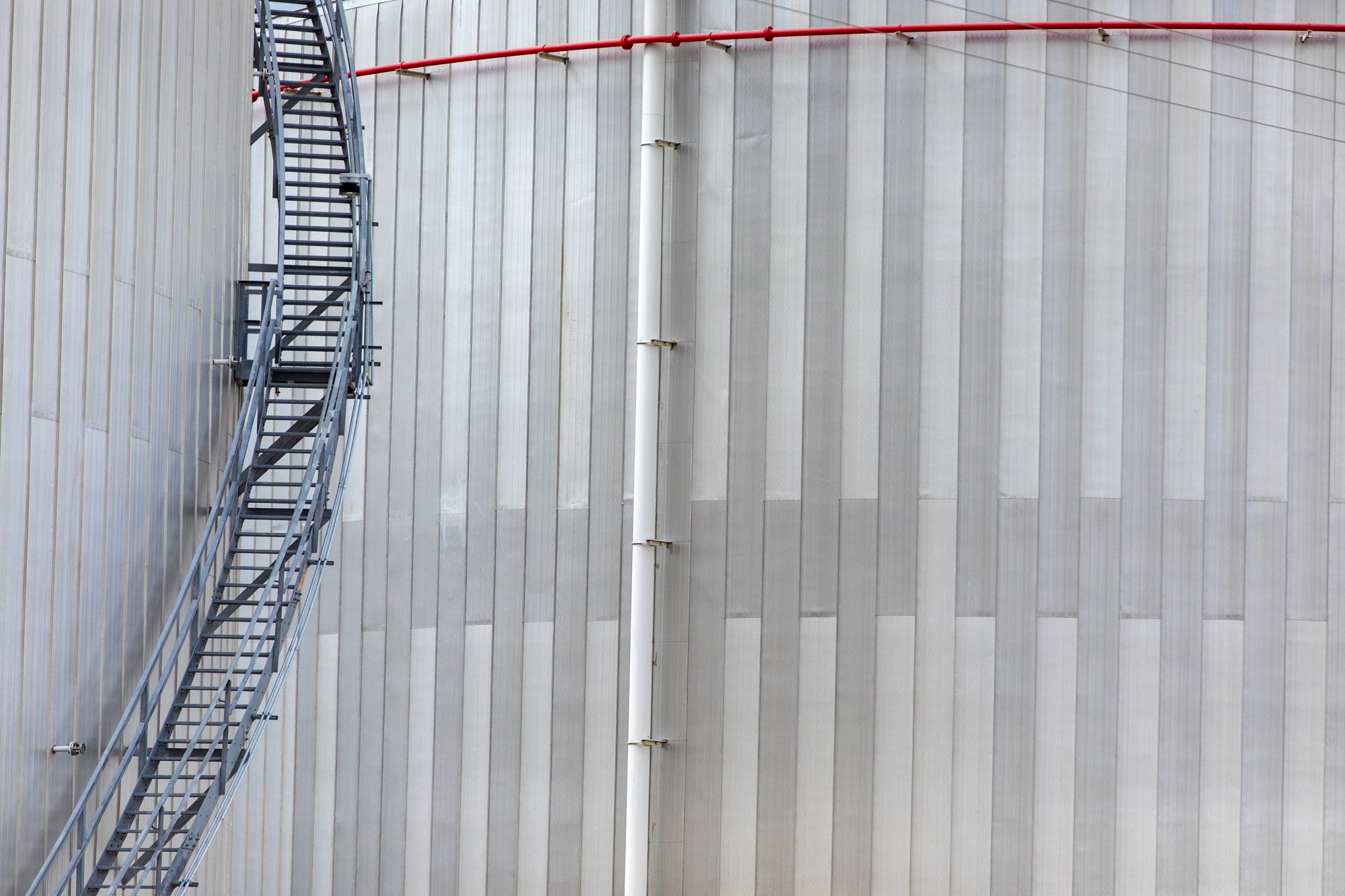 A metal exterior wall of a building with a stairway and a drainpipe.