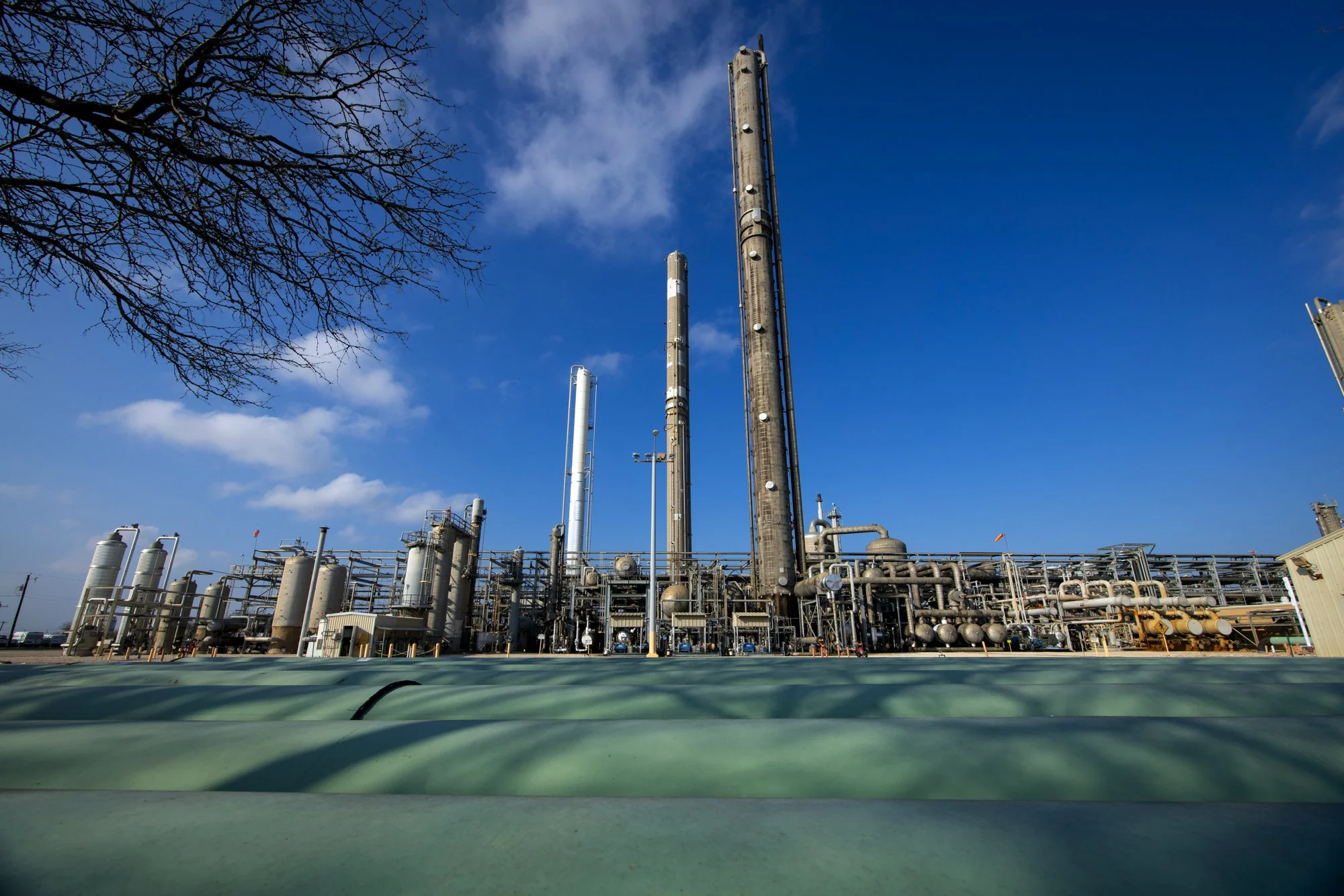 Industrial oil refinery with tall distillation towers under a blue sky with some clouds.
