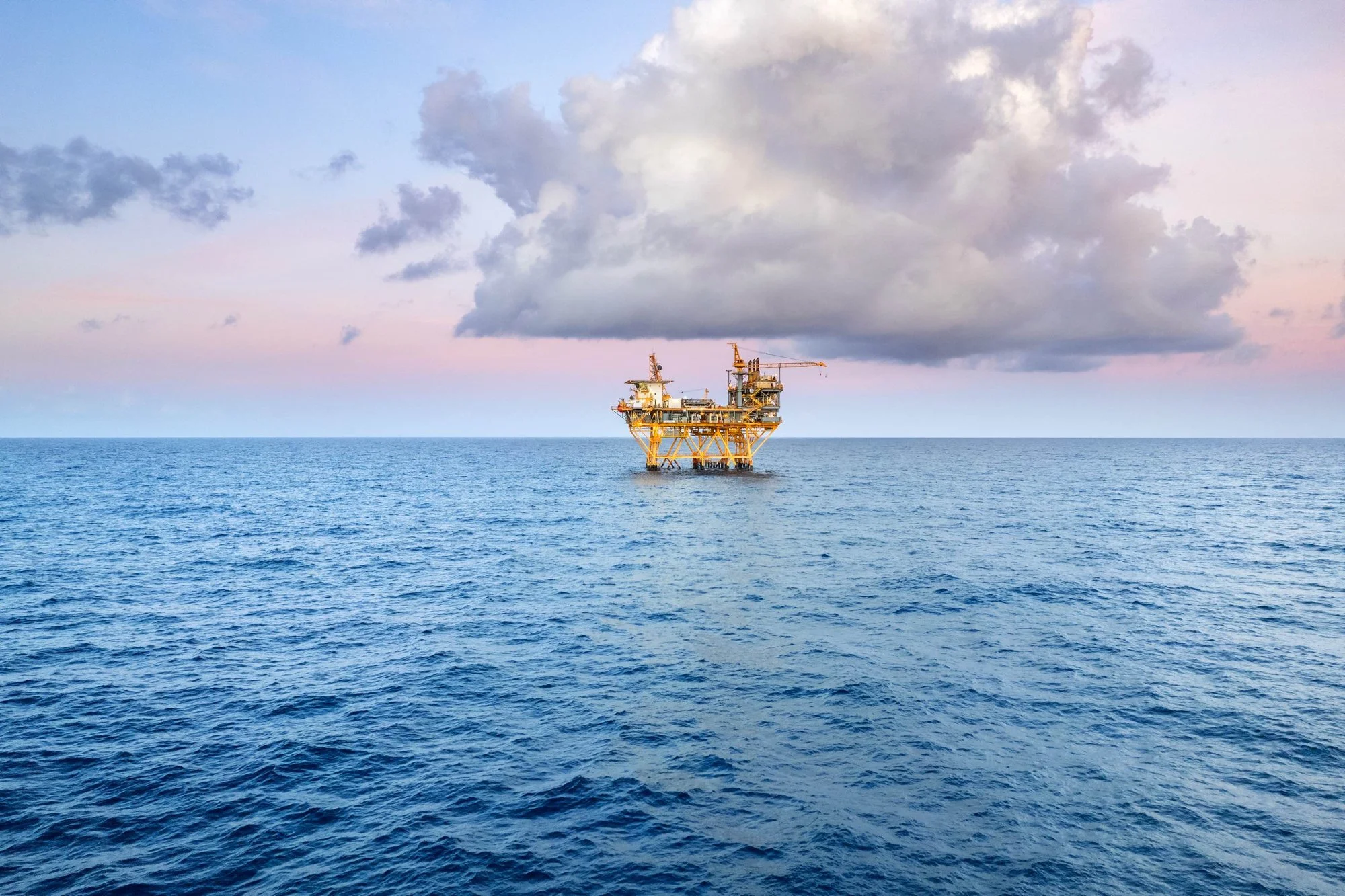 Offshore oil rig in the ocean with cloudy sky.