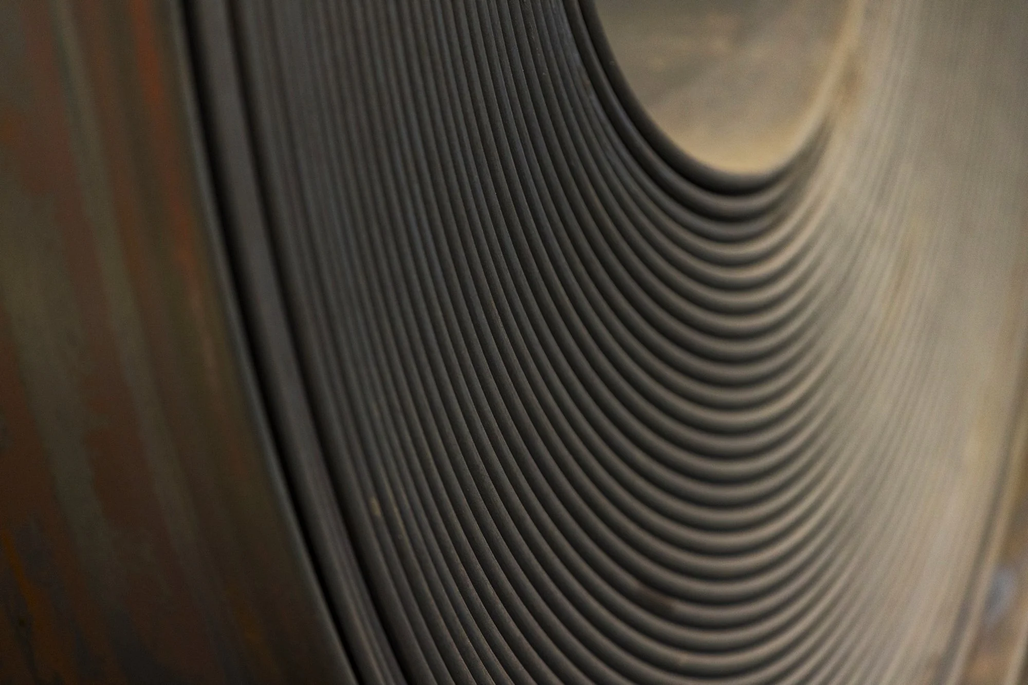 Close-up of a metallic object with concentric curved ridges and a circular indentation.