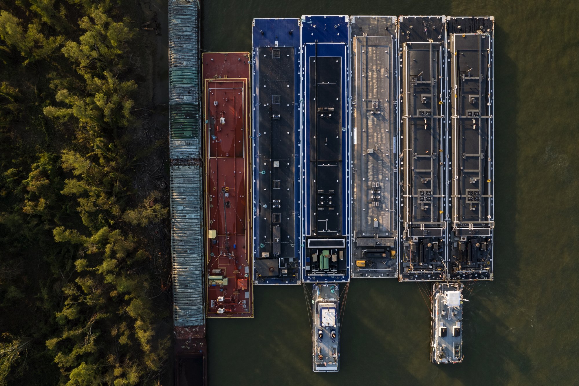 Aerial view of a large boat docked in a waterway, with a wooded area on the left side.