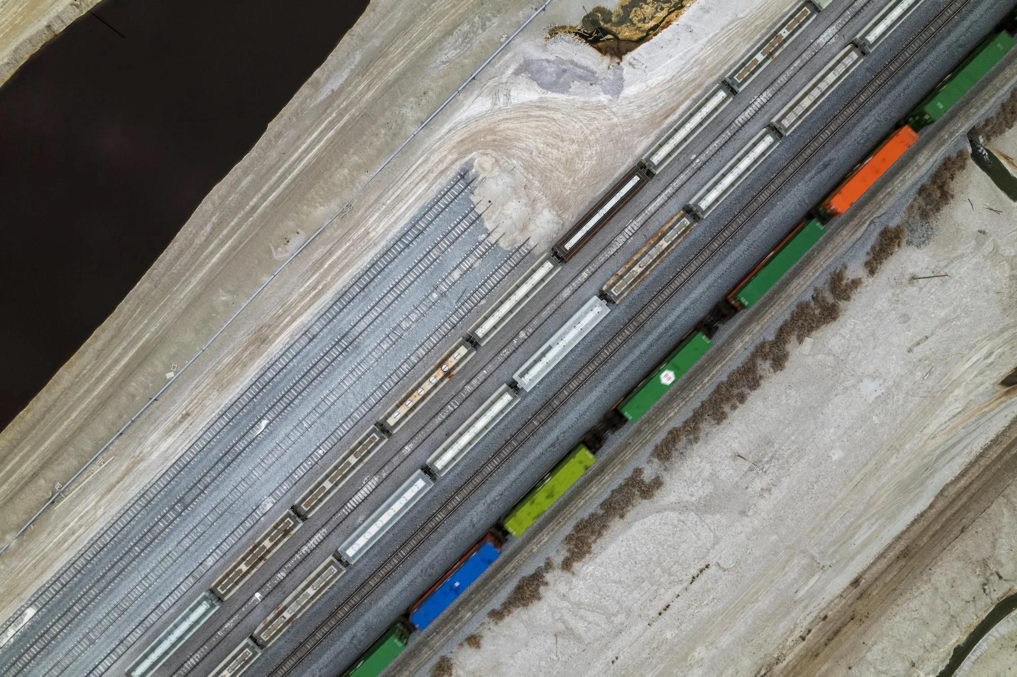 Aerial view of a model train layout with multiple train tracks and freight cars on an indoor or outdoor surface.