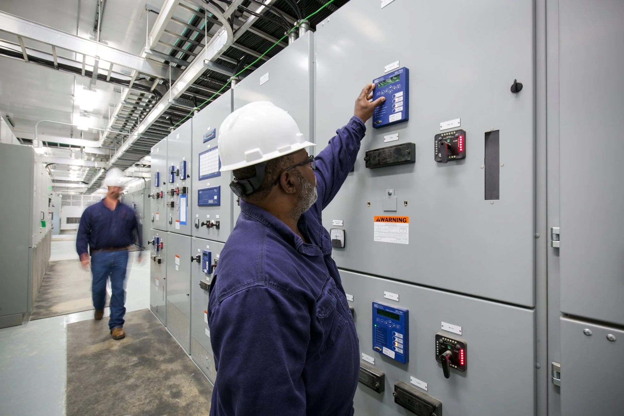 Electricians inspecting electrical panels in a power plant