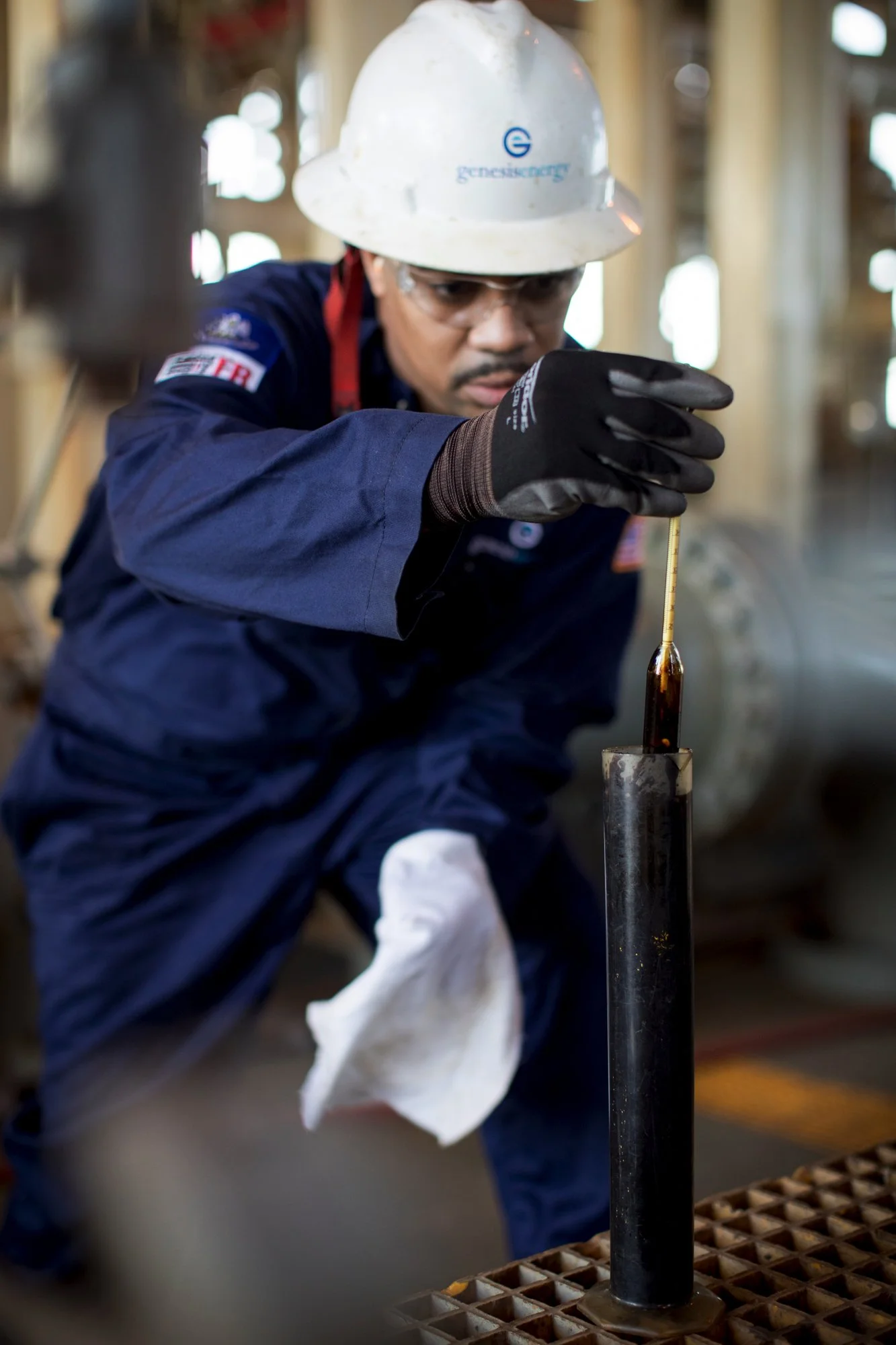 A worker in safety gear using a tool to perform maintenance or inspection on a large industrial pipeline or cylinder.