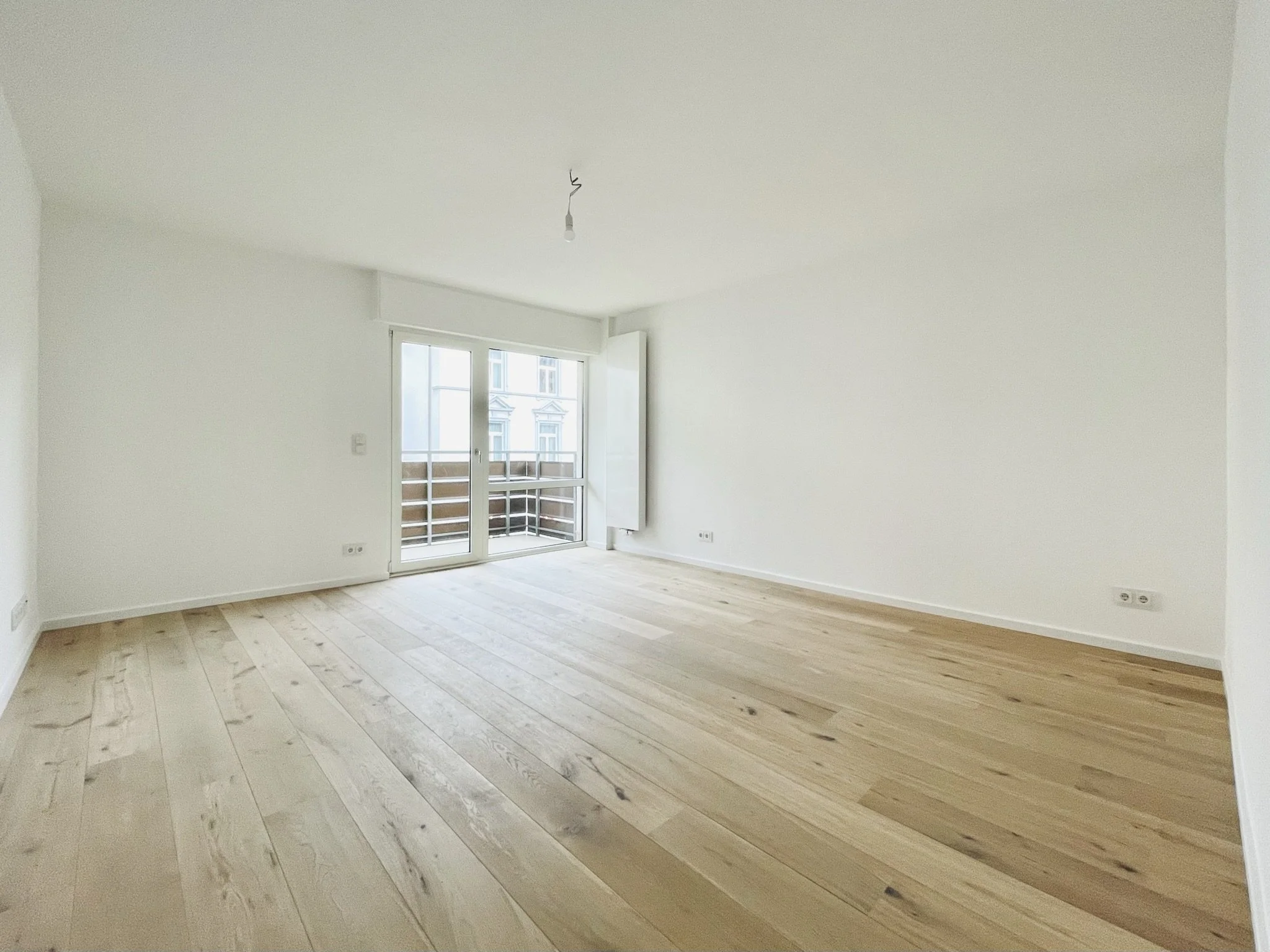 Sanierung Frankfurt Westend Wohnung Wohnzimmer nach Sanierung mit Parkett und neuem Heizkörper