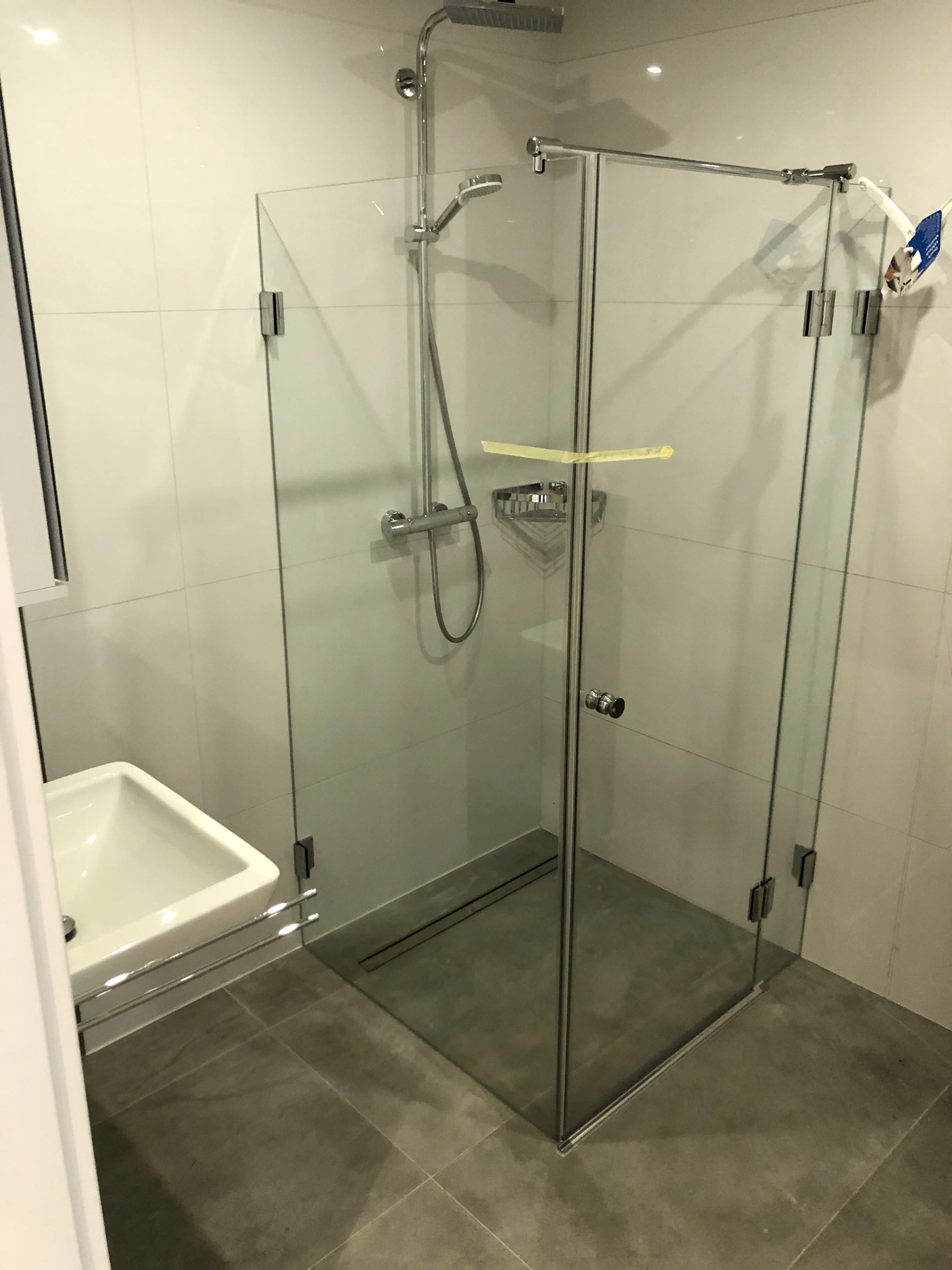 Duschkabine mit Glaswänden in einem modernen Badezimmer, daneben ein Waschbecken.