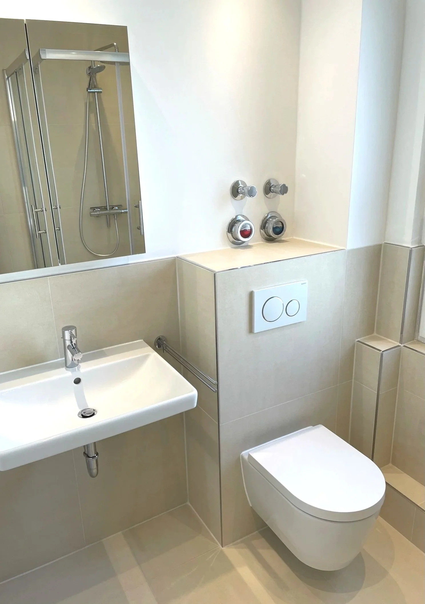 Kleines Badezimmer mit WC, Waschbecken, Spiegel und Dusche, alles in neutralen Tönen.