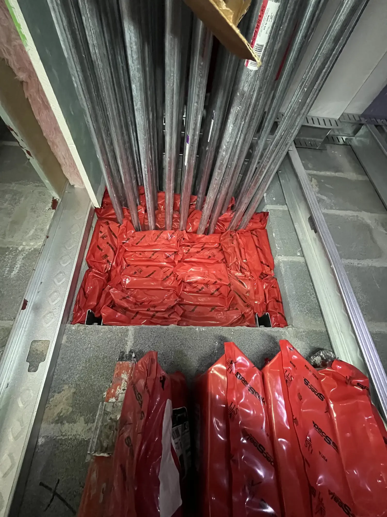 Several long metal rods standing upright inside a construction site, secured with red protective wraps around the base.