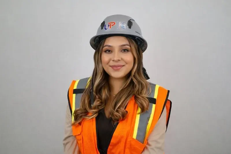 Woman wearing a hard hat and high-visibility orange safety vest