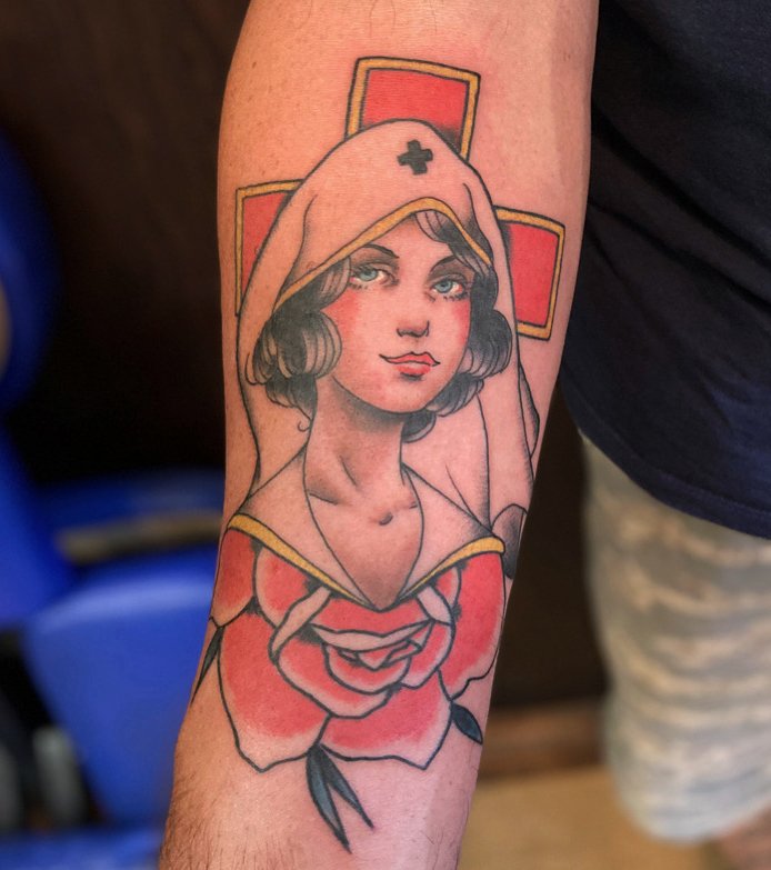 Tattoo of a woman with a nurse's cap featuring a cross, a red rose, and a yellow cross in the background.