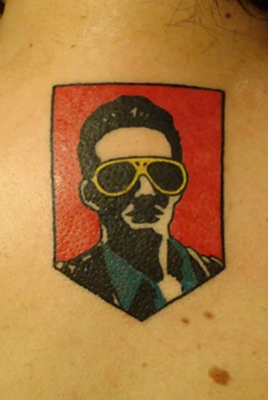 Tattoo of a man wearing sunglasses with a red background.