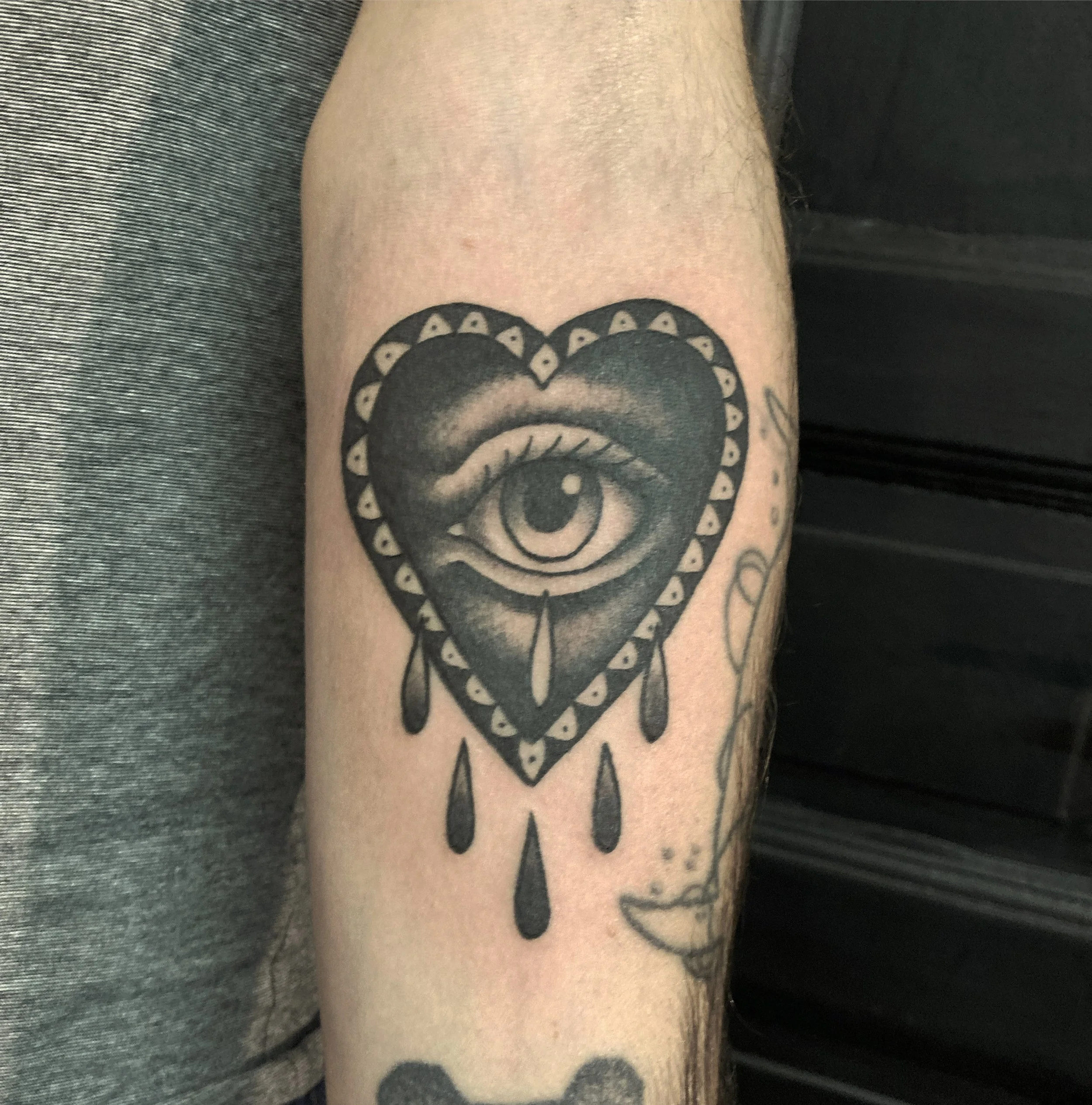 Tattoo of a heart with an eye in the center and tears dropping from the eye.