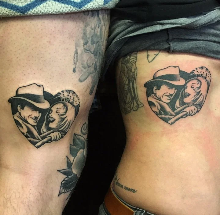 Two tattoos of a smiling couple within a heart outline, with the woman having blonde hair and the man wearing a hat, on the thighs of two different people.