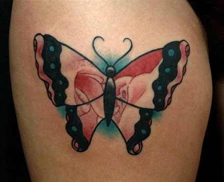 Tattoo of a butterfly with black and pink wings on skin.