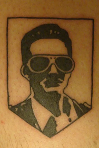 A tattoo of a man wearing sunglasses and a suit, depicted in a simple black outline style.