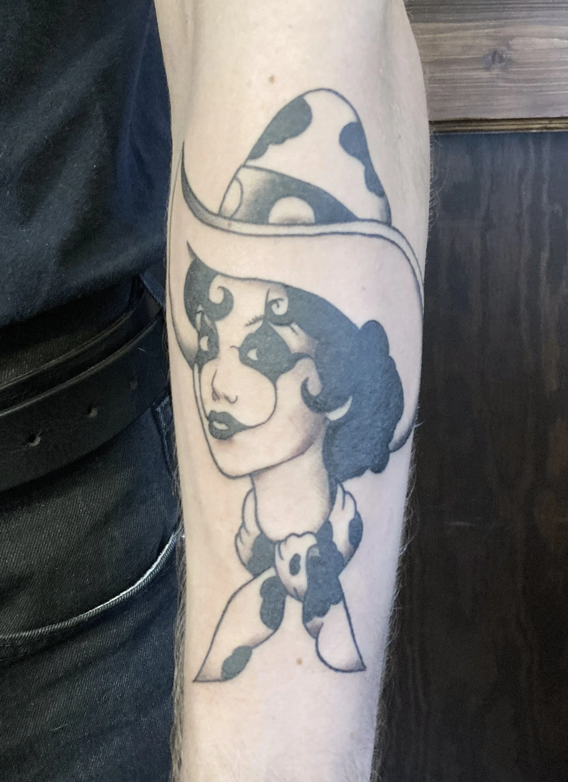Tattoo of a woman with curly hair and a hat, wearing a bandana with a polka dot pattern.