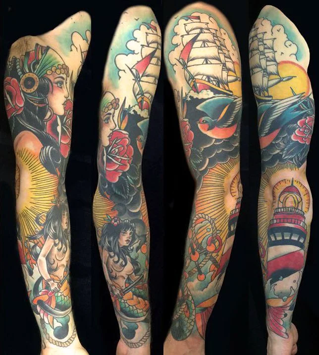 Colorful full sleeve tattoos depicting a woman, a ship with sails, a bird, a lighthouse, and various nautical and fantasy elements.
