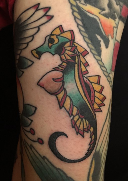 Colorful tattoo of a seahorse with geometric and watercolor elements on a person's arm.