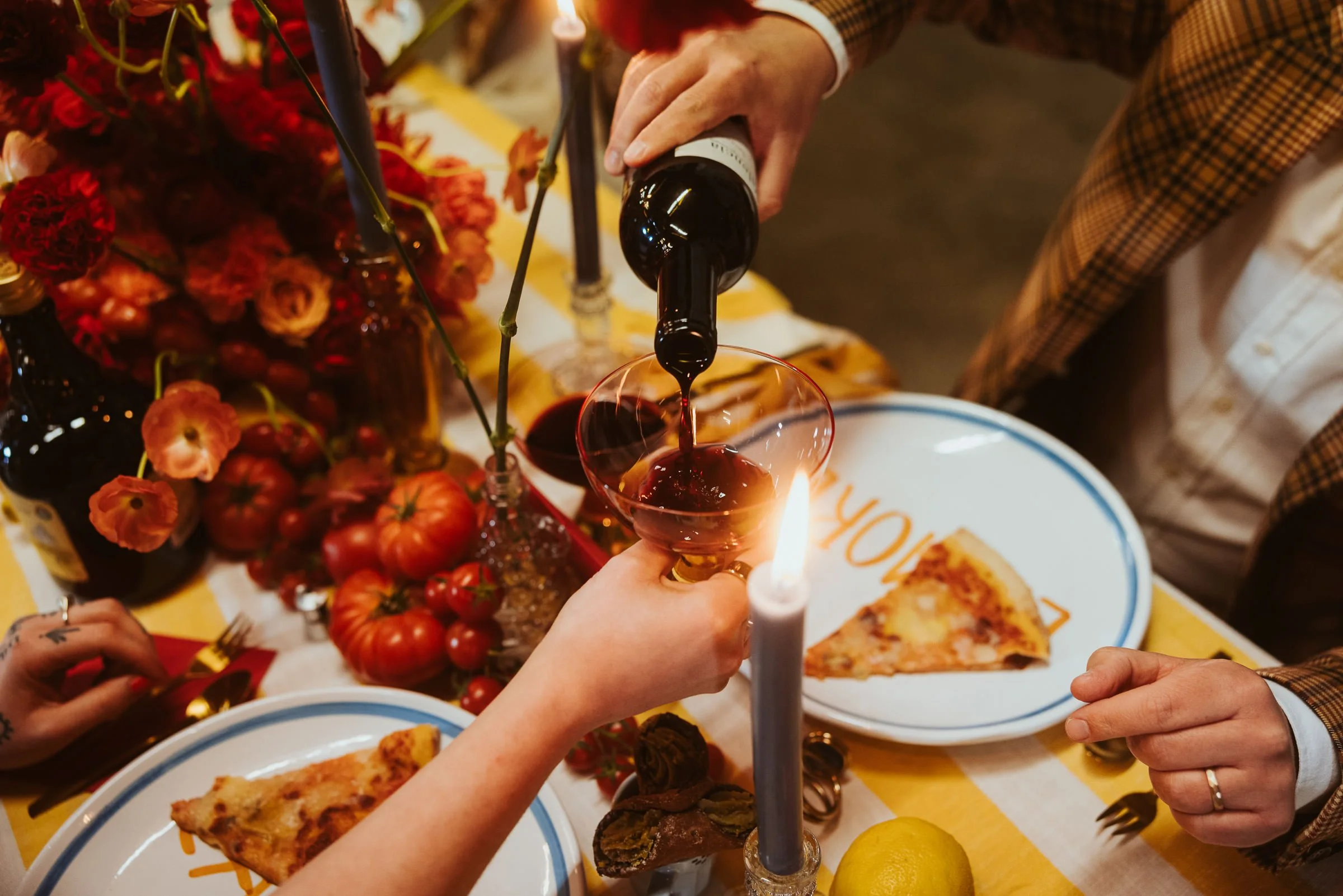 Menschen stoßen bei einem Fest mit Rotwein an, umgeben von Essen und Dekorationen.