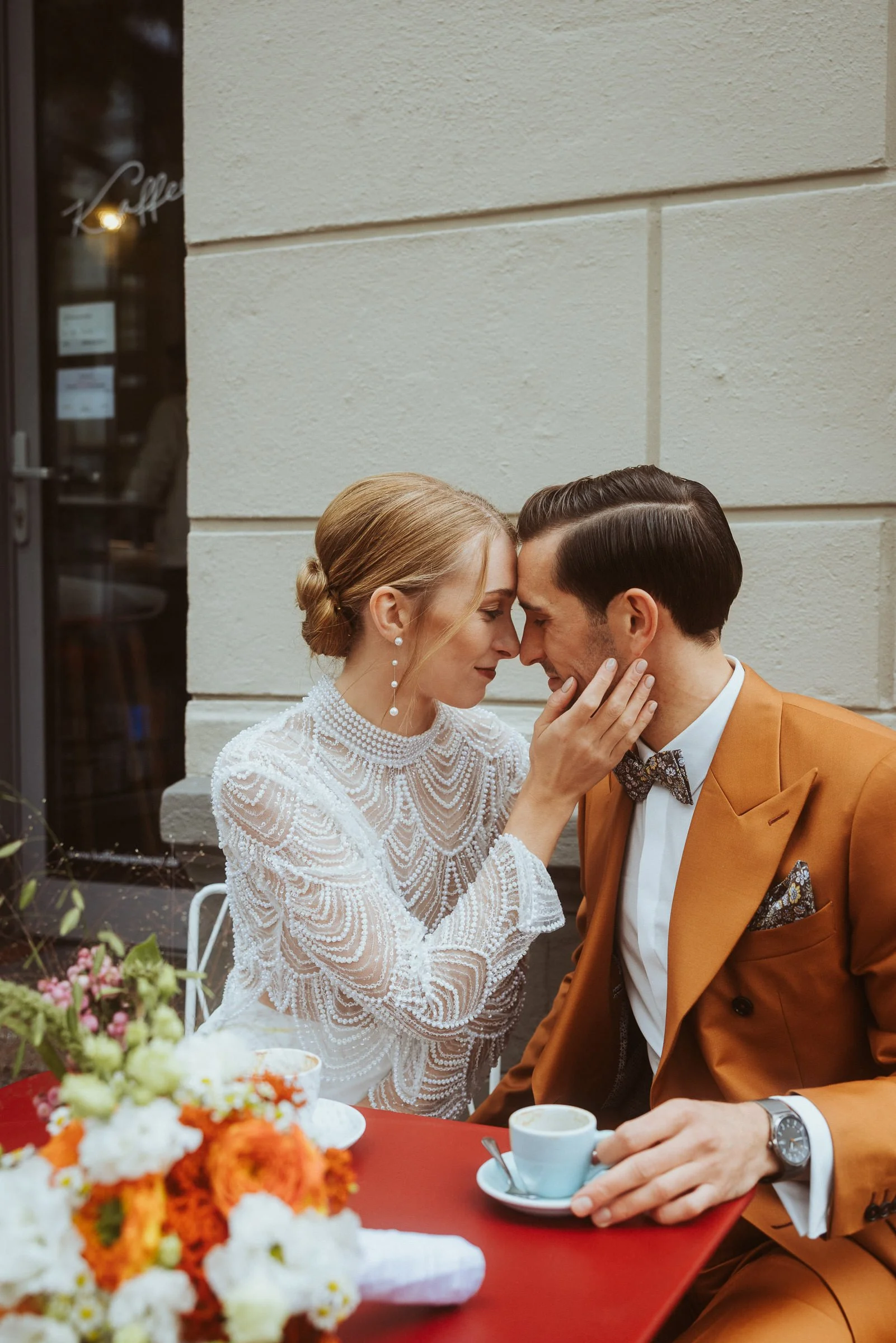 Hochzeitspaar berührt sich innig an einem Cafétisch in der Kaffeegießerei Münster