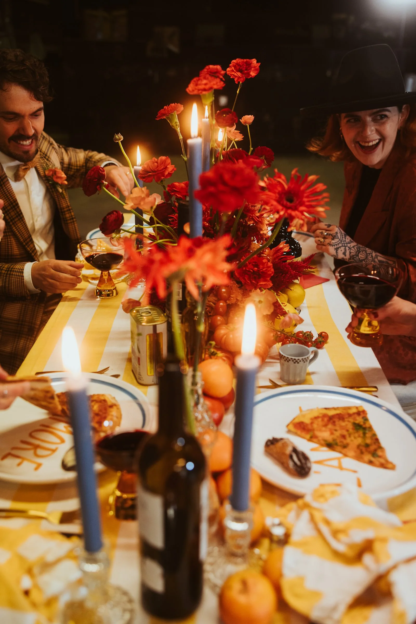 Lachende Hochzeitsgäste genießen Pizza und Wein an einer farbenfrohen Tafel im Skaters Palace Münster