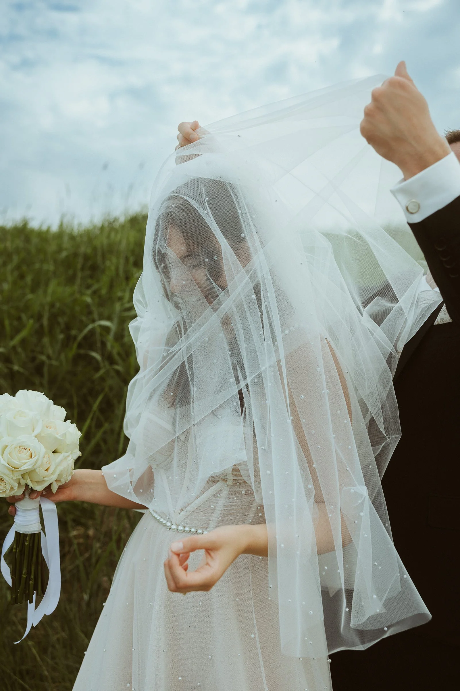Braut mit Schleier und weißem Rosenstrauß bei einer Strandhochzeit in Hooksiel an der Nordsee