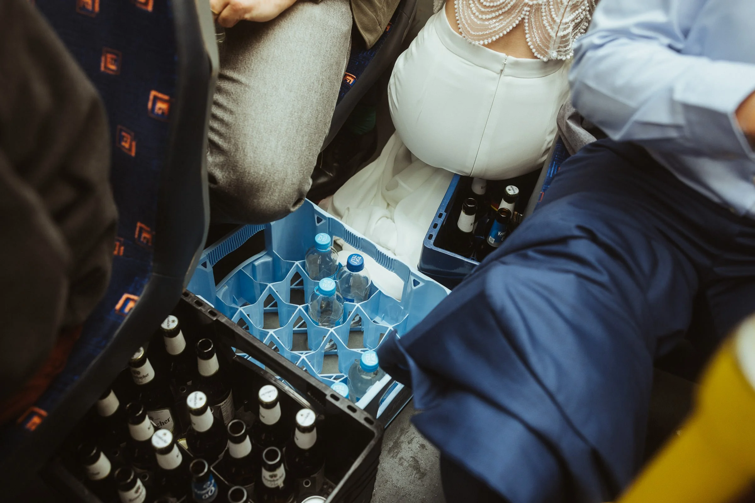 Menschen auf einem Flugzeug sitzen, das Foto wurde aus einer erhöhten Position aufgenommen, zeigt vollen Sitzbereich, gefüllte Getränke im Kühler, Kaffee- oder Kaugummiflaschen neben den Sitzen.