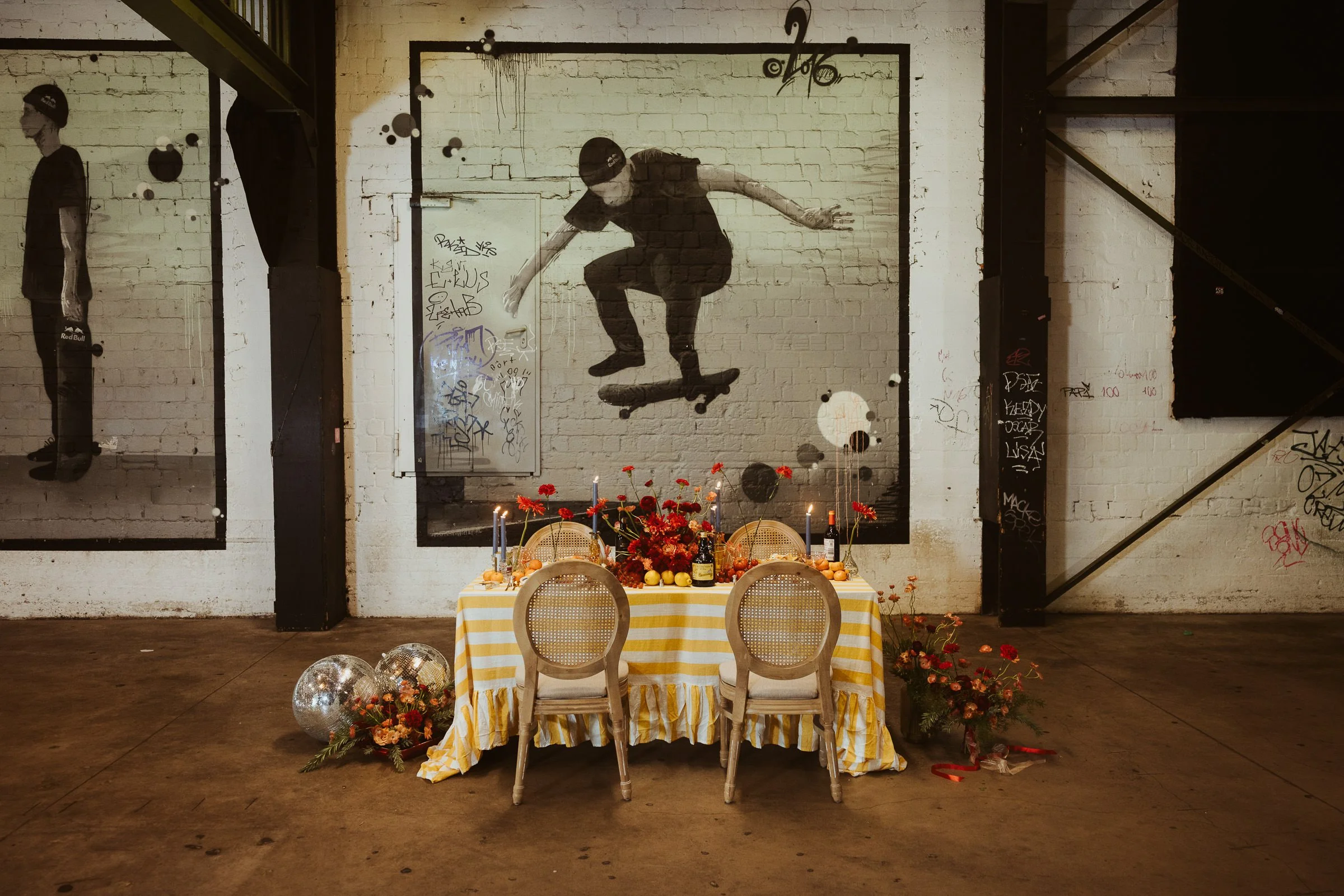 Hochzeitspaar sitzt an einer farbenfrohen Tafel mit roten Blumen im Skaters Palace Münster