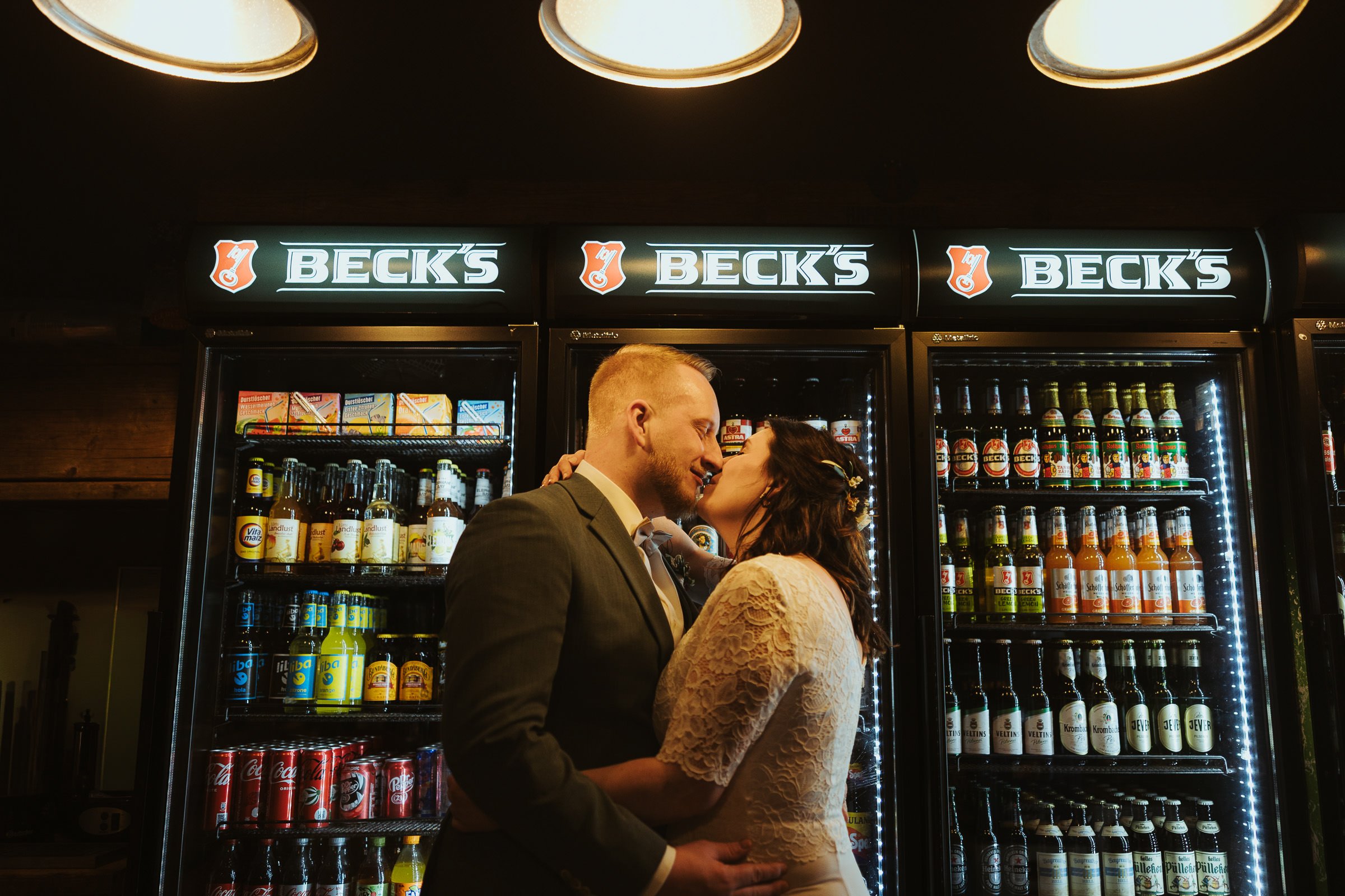 Hochzeitspaar küsst sich vor Getränkekühlschränken in einem Kiosk am Hansaring in Münster