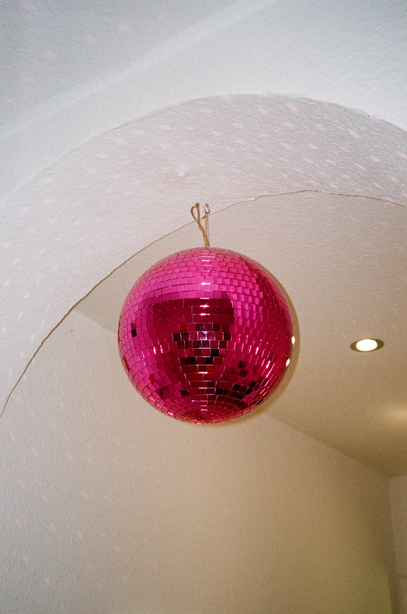 Eine pinkfarbene Disco-Kugel hängt von der Decke.