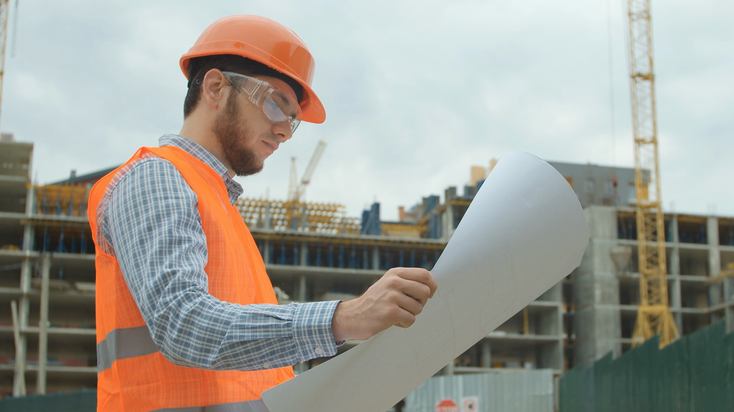Man wearing orange construction clothes looking at a spec sheet
