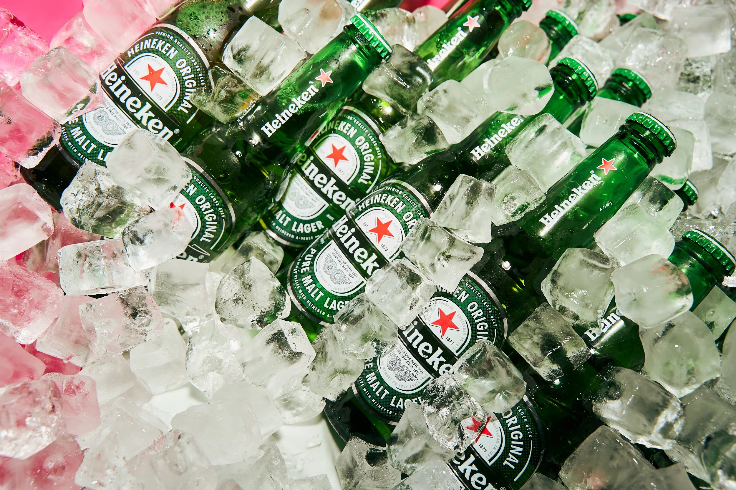 Several bottles of Heineken beer surrounded by ice cubes in a cooler or ice bucket.