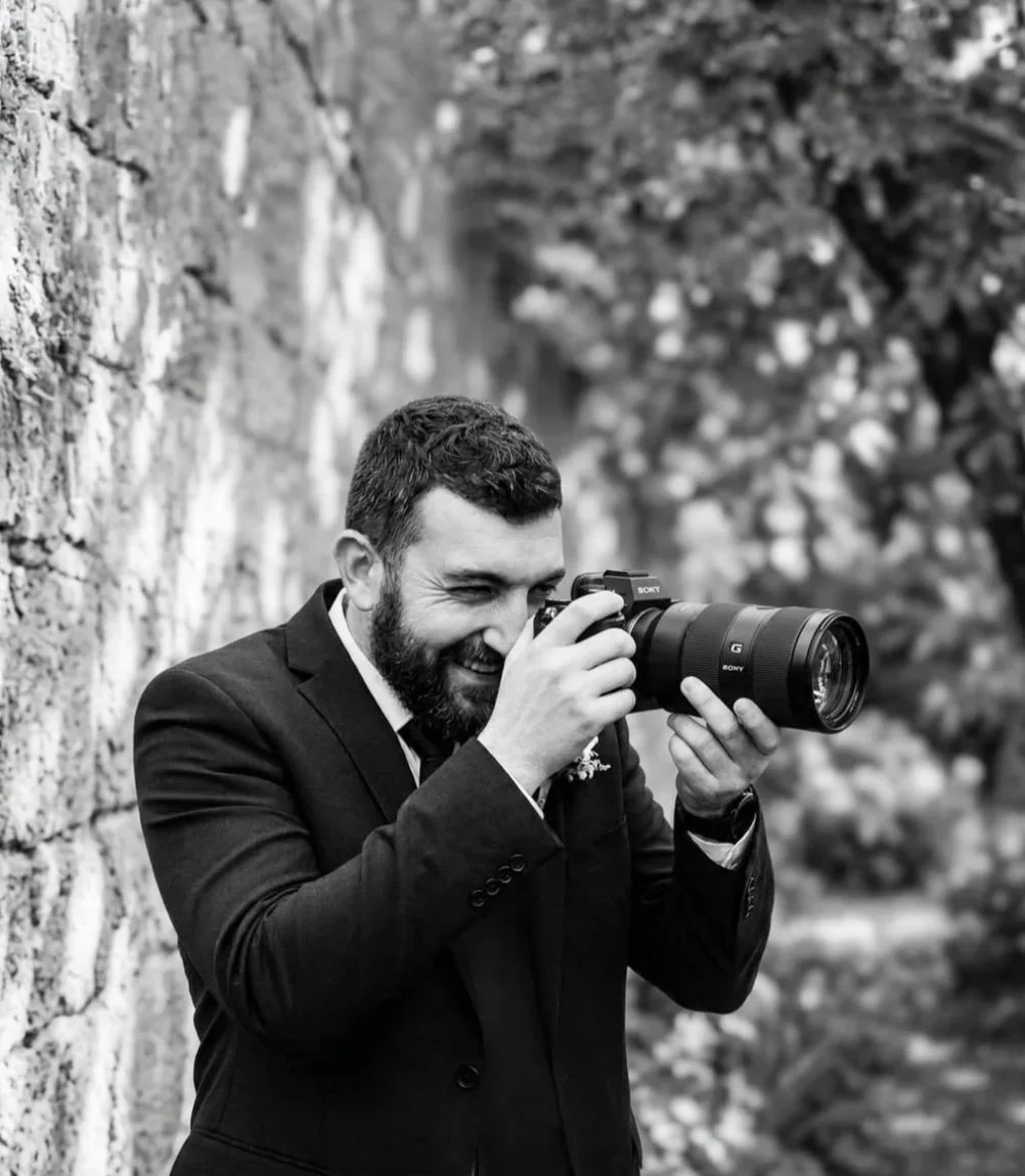 Alex Gell holding a camera on location, wedding and lifestyle photographer.