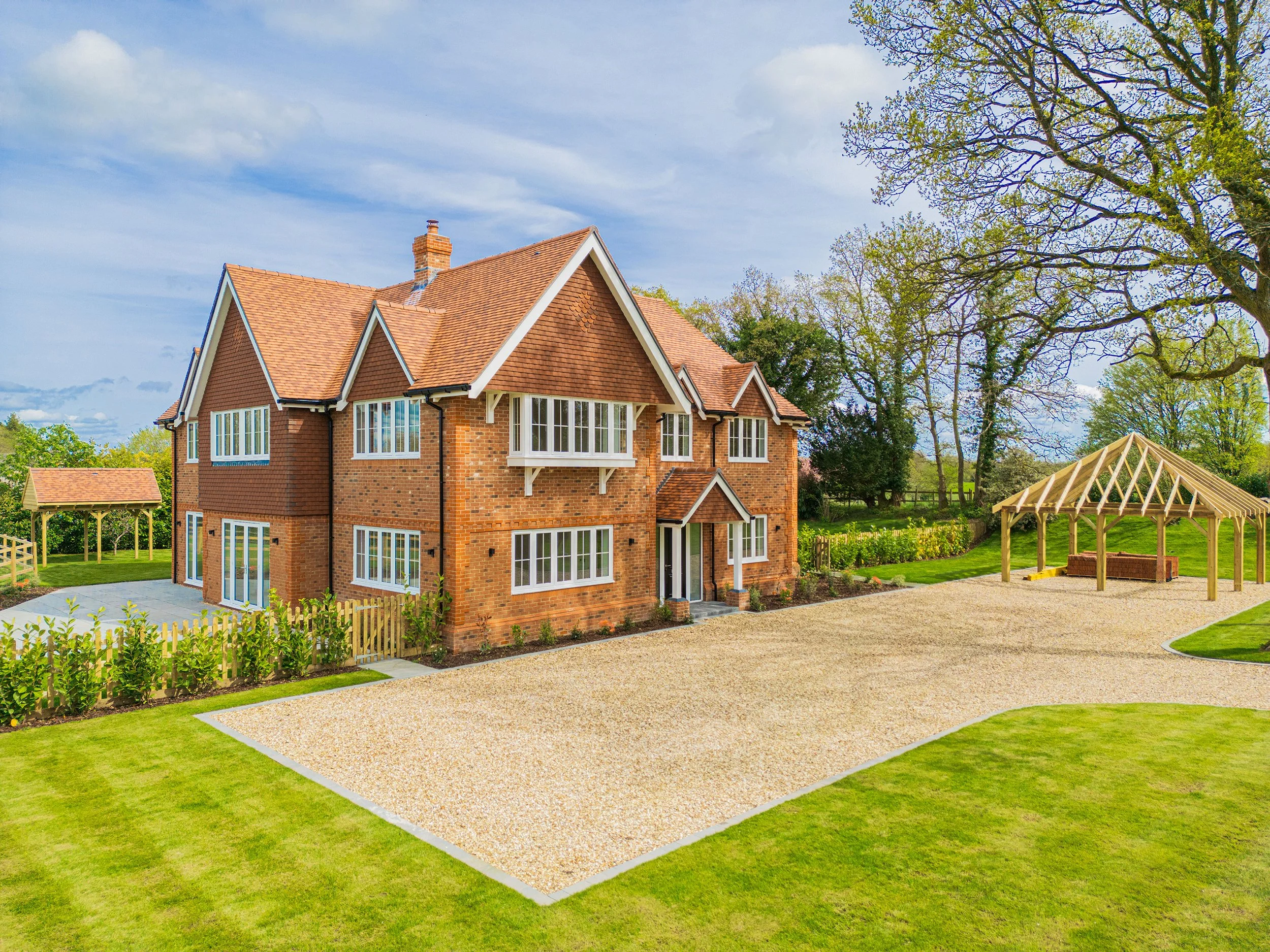 A large brick house with a landscaped yard and a wooden gazebo under construction.