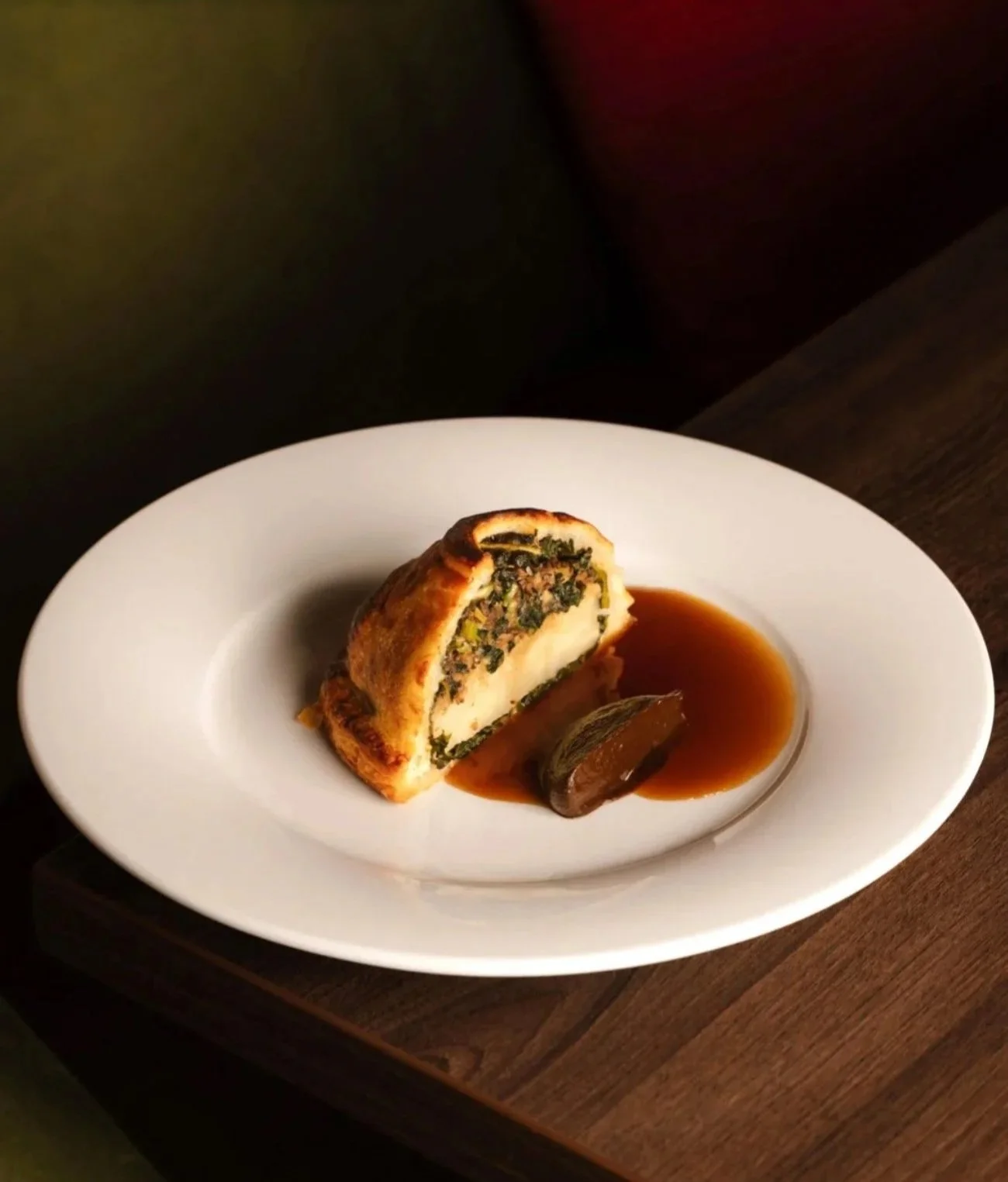 Plated savoury pastry dish with a rich sauce at a restaurant, fine dining culinary lifestyle photography by Alex Gell.