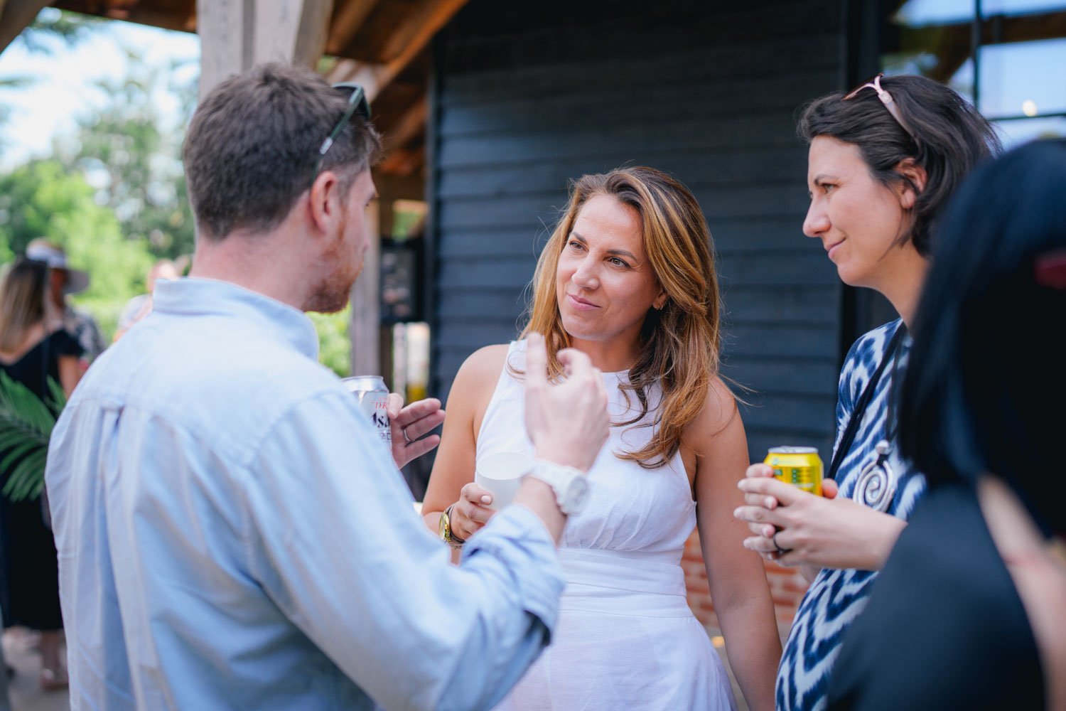 People socializing outdoors, holding drinks at a gathering.