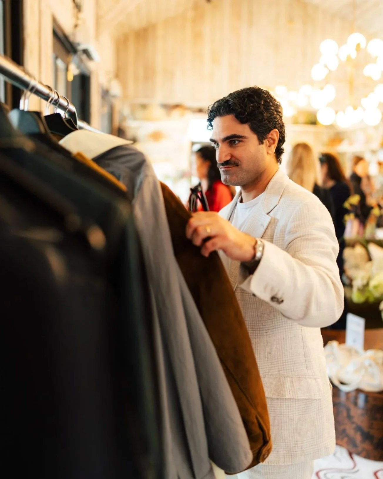 Man browsing a clothing rack at a fashion brand event in London, event lifestyle photography by Alex Gell.