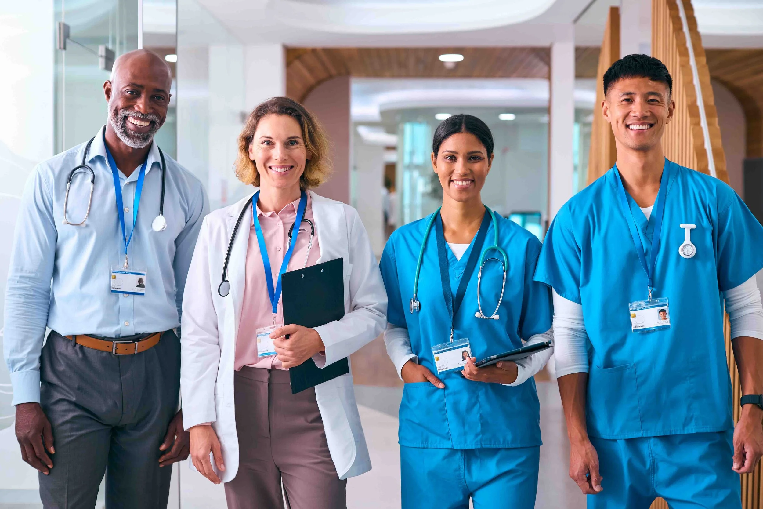 Group of four healthcare professionals, including doctors and nurses, standing in a hospital corridor.