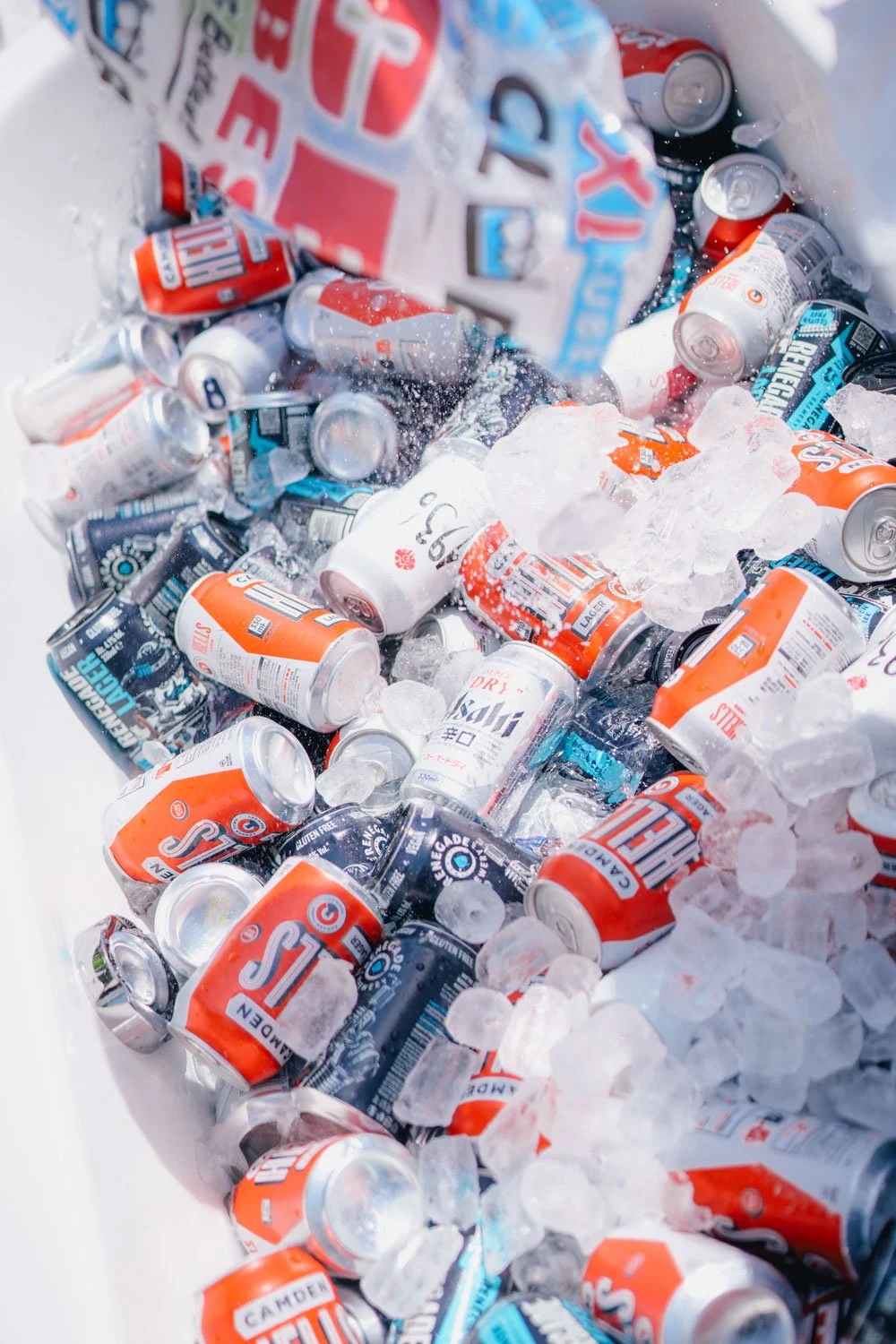 A cooler filled with ice and various cans of beer and energy drinks.