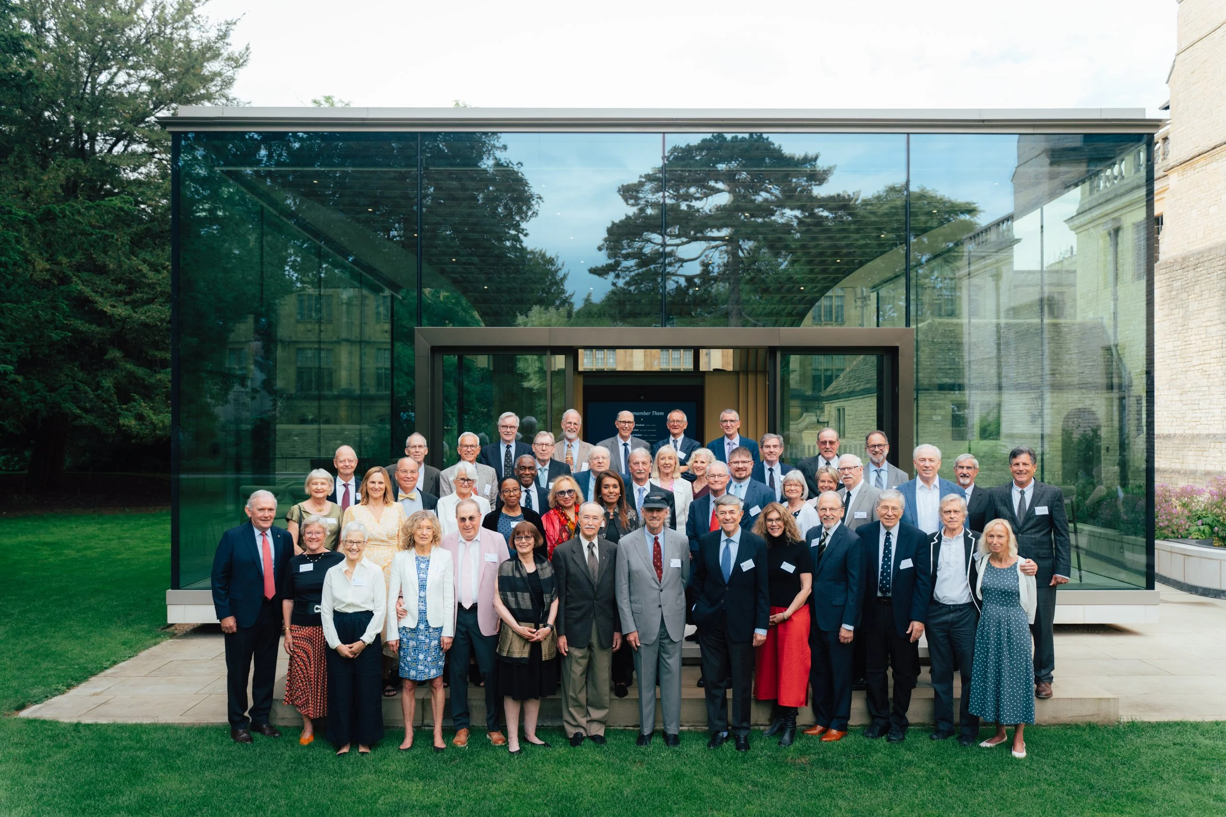 Group of people gathered outdoors in front of a modern glass building for a photo.