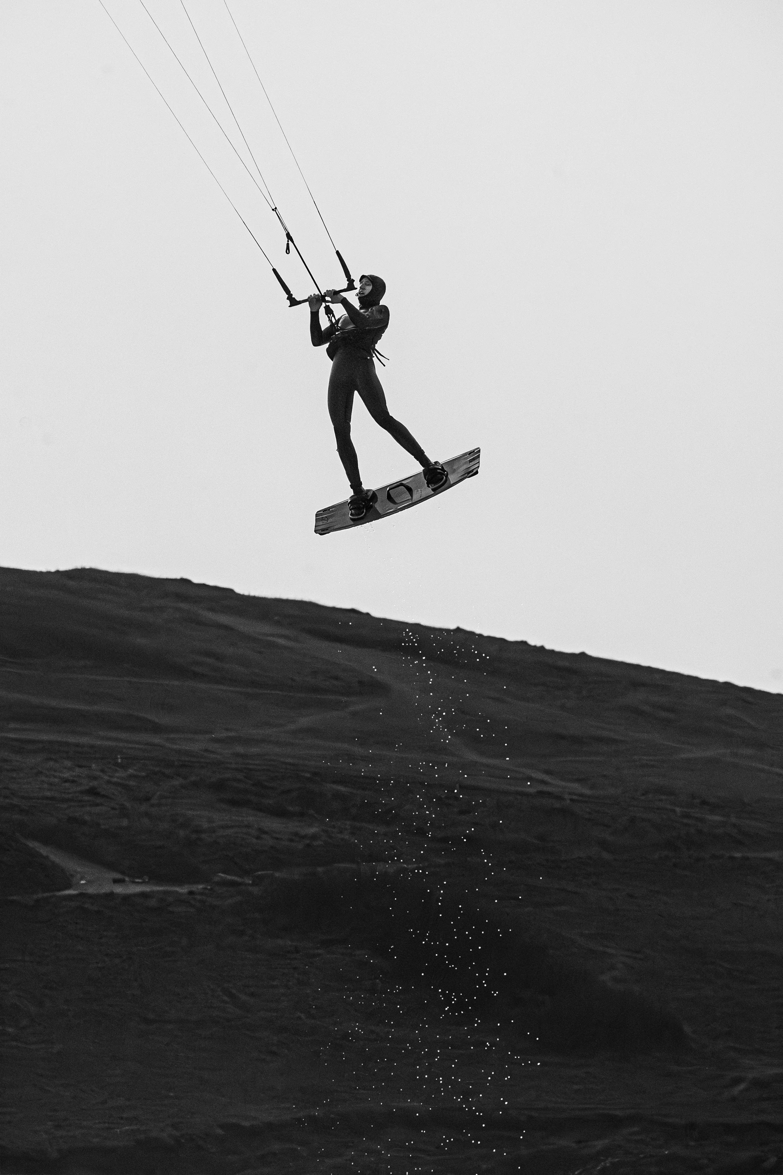 A person kiteboarding on a hill in black and white.