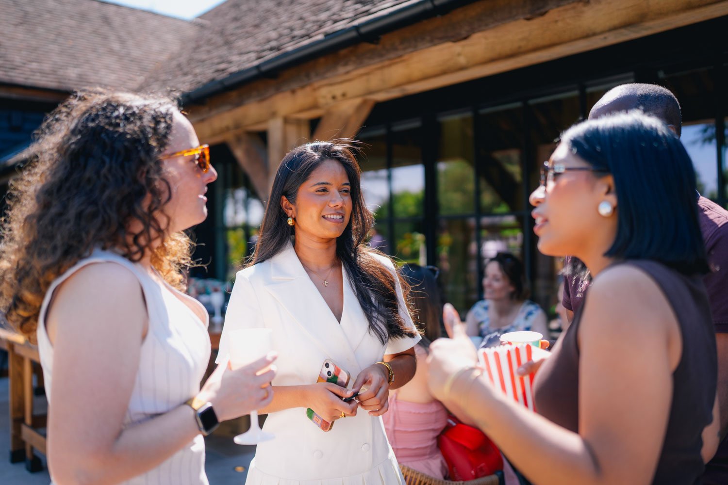 Group of women talking and smiling outdoors during daytime at a gathering.