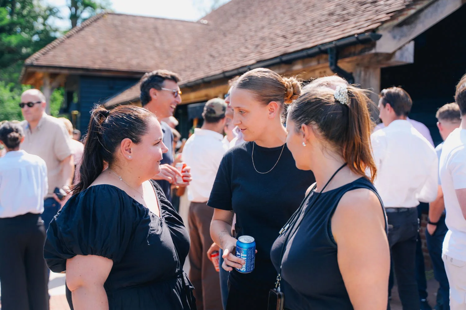 People socializing outdoors, engaged in conversation at a gathering near a building with a tiled roof
