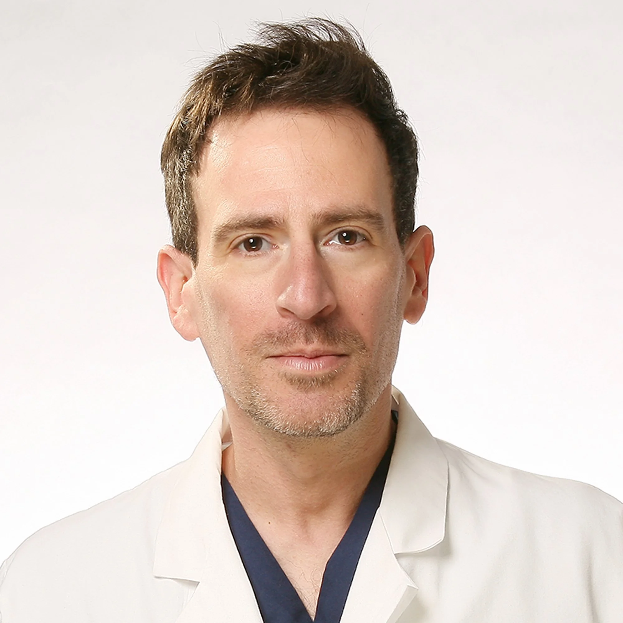 Photo of Dr. Gregory Charlop, MD, DipABLM, wearing a white coat with light facial hair.