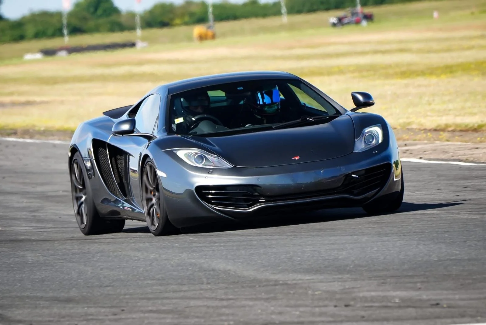 A black sports car with a sleek design on a race track during daytime.
