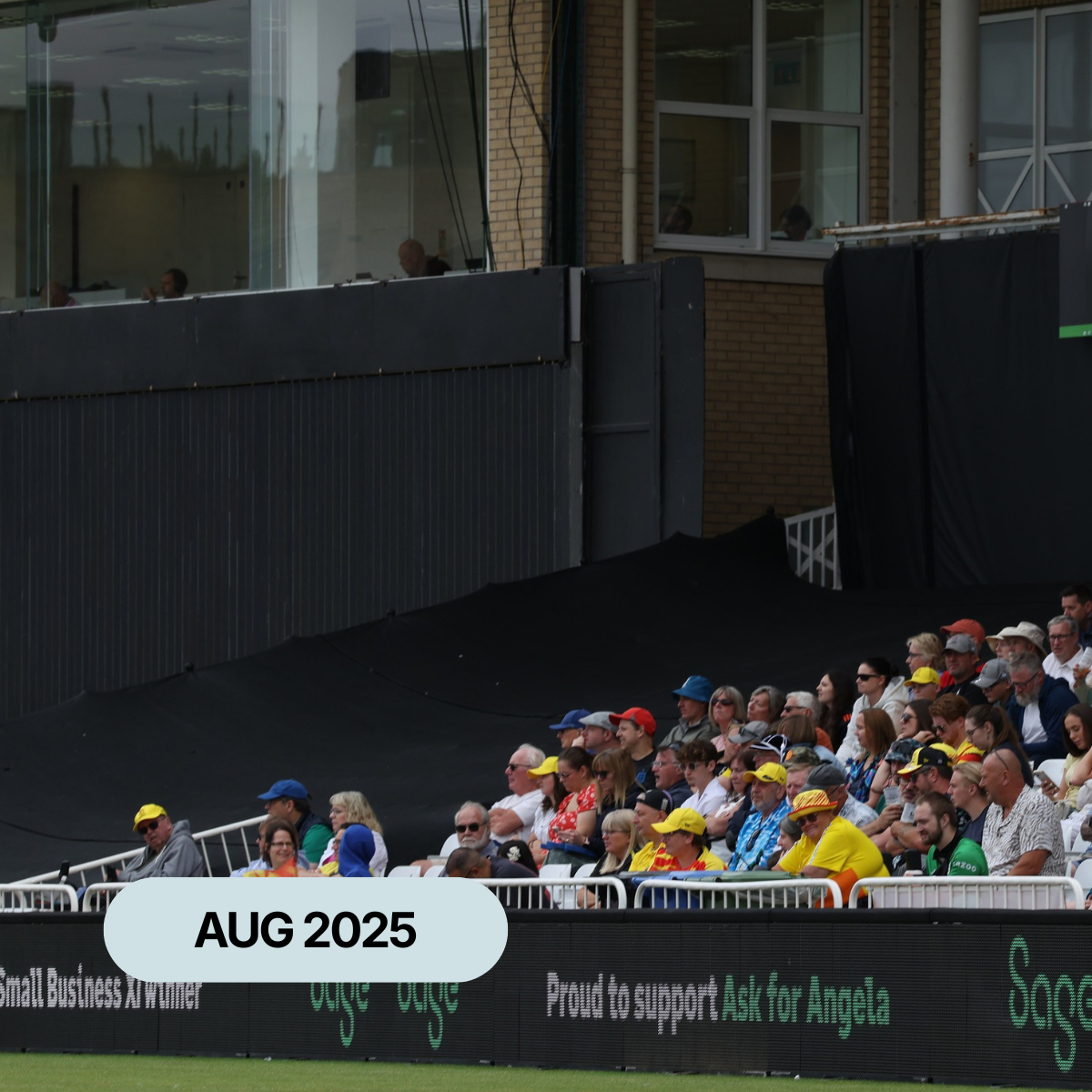 Spectators at a cricket ground with Ask for Angela displayed on advertising boards around the pitch.