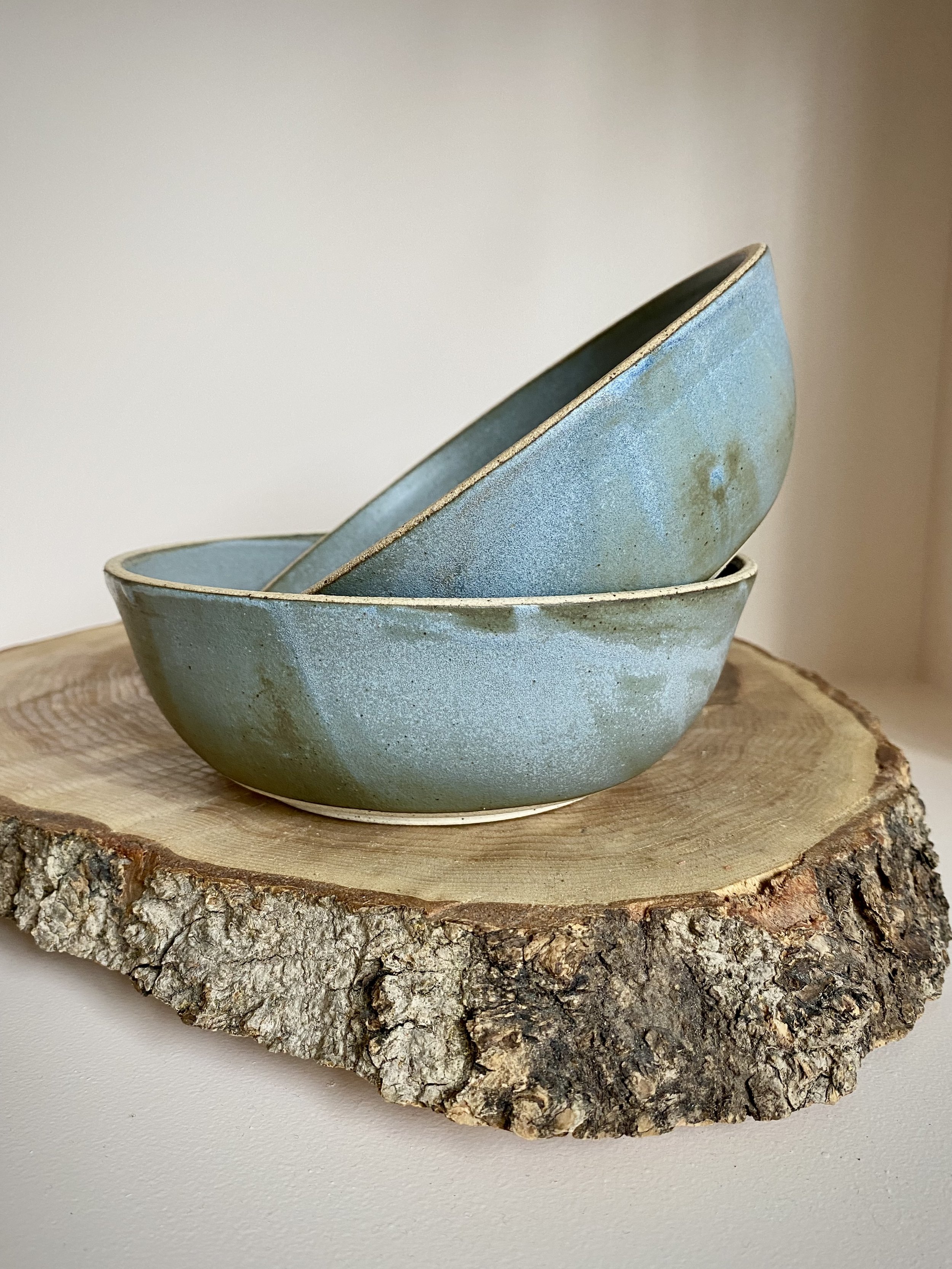 Stack of three blue ceramic bowls on a tree stump